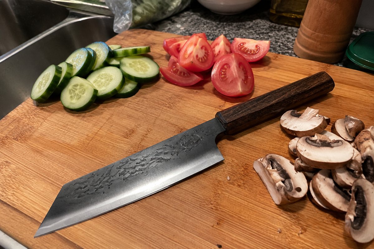 Kiritsuke knife on a cutting board with vegetables