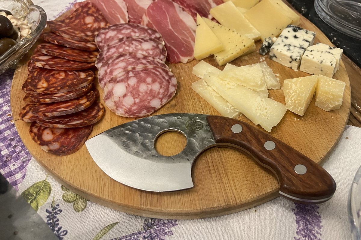 Multipurpose knife on a board of cheese and cured meat